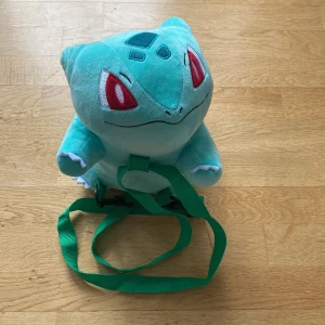 Bulbasaur Pokémon väska - Säljs för original priset. Har en liten ficka i bak som en mobil kan få plats i, 26cm i längd, 17cm i bredd och 24 i höjd.