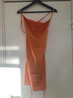 Orange kort satinklänning - Orange kort satinklänning från PLT med öppen/smörad rygg. Aldrig använd, endast provad, lappar kvar