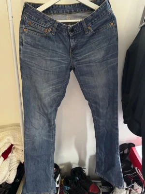 Blå Levi's bootcut jeans - Klassiska blå Levi's jeans med bootcut passform och fem fickor. Jeansen är även low-waist. Det har en snygg tvättad look och detaljer i kopparfärgade nitar. Tillverkade i slitstark denim med Levi's ikoniska läderpatch bak i midjan. Passar perfekt för dom som har storlek 36 i jeans, på mig är dom lite långa(är 163cm)