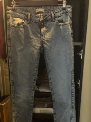 Blå bootcut jeans med broderade fickor - Säljer ett par blå bootcut jeans med snygga broderade detaljer på bakfickorna. Jeansen har klassisk femficksmodell och är tillverkade i ett slitstarkt denimtyg. Perfekt för dig som gillar en avslappnad men ändå trendig look. Dom är mindre än storleken säger så typ storlek 34.