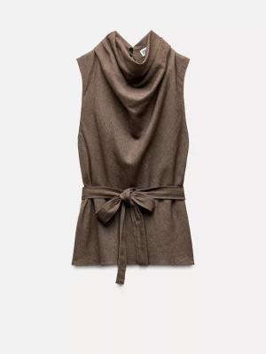 Brun väst med knyt och draperad krage - Snygg brun väst med draperad krage och brett knytband i midjan. Ärmlös modell i mjukt tyg som ger en avslappnad men ändå chic look. Perfekt att styla över en långärmad tröja eller skjorta för extra lager.