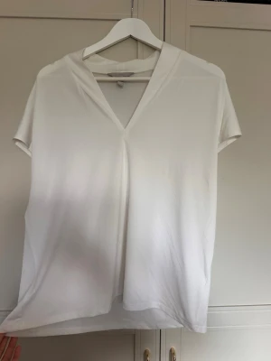 Vit v-ringad kortärmad topp - En enkel och stilren vit topp med v-ringning och korta ärmar. Perfekt att matcha med jeans eller kjol för en clean look.