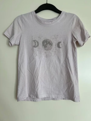 T-shirt - Fin T-shirt med måne!   Acceptabelt skick. Lapp borttagen så vet inte vart den är köpt någonstans tyvärr. Men det är 100% bomull och storlek XS.   Längd: ca 57-58 cm Axel bredd: ca 36 cm