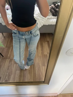 Ljusblå raka jeans med hög midja - Säljer ett par ljusblå jeans med raka ben och hög midja. Jeansen har tydliga sömmar framtill, klassiska fem fickor och bälteshällor. Materialet är denim i bomull och passformen är relaxed och trendig.