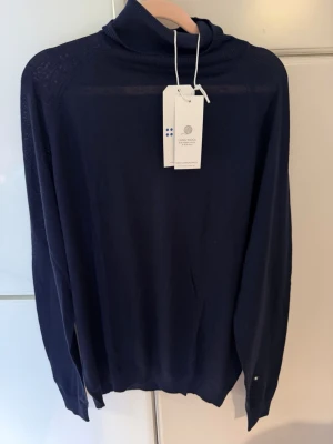 Mörkblå polotröja från Kopenhagen - Snygg mörkblå stickad polotröja från Kopenhagen i mjuk merinoullsblandning. Tröjan har lång ärm, hög polokrage och en klassisk, stilren look som passar perfekt till många outfits.