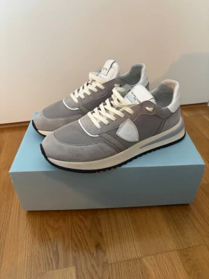 Philippe Model Tropez 2.1  - Philippe Model Tropez 2.1 sneakers grå – strl 43  Philippe Model Paris Tropez 2.1 sneakers i grått med detaljer i mocka, mesh och vitt läder.  Modell: Tropez 2.1 Low Man / Technique Gris Modellkod: TYLU TC04 Storlek: EU 43 / US 9.5 / UK 9 Originalkartong medföljer.  Endast använda under en kort period, cirka en månad, och sparsamt använda. Skorna är därför i mycket fint begagnat skick. Ovandelen är välbevarad. Mindre bruksspår/smuts finns på sulorna, vilket framgår av bilderna.