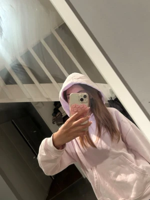 Ljusrosa hoodie med huva - Säljer en ljusrosa hoodie med klassisk huva och stor magficka. Hoodien har ribbade muddar vid ärmsluten och är gjord i ett mjukt material som känns skönt mot huden. Perfekt för dig som gillar en chill och avslappnad stil.
