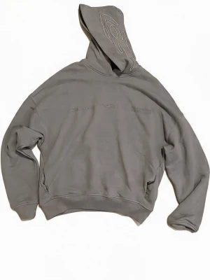 Grå hoodie med tryck och huva - Säljer en grå oversized hoodie med trycket 'out of core' på ryggen och diskreta detaljer framtill. Huvan har ett vitt grafiskt mönster. Hoodien har ribbade muddar vid ärmslut och nederkant. Perfekt för en avslappnad streetwear-look. Passar nån i S-M. Har bara använt 1gång💕