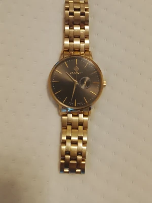 Gant Klocka Nypris~3000kr, Utmärkt skick - Utmärkt skick, Gant Park Hill III (serie no. G1050),gold ion plating stainless steel, grå/mörk urtavla, gulddetaljer, Japan-urverk (Miyota), mineralglas, 5 ATM vattentålighet, 41,5 mm diameter.  Nypris~"3000kr" Begagnade i utmärkt skick går för "2300kr. Skicka ett meddelande vid intresse! Mvh Kaninen