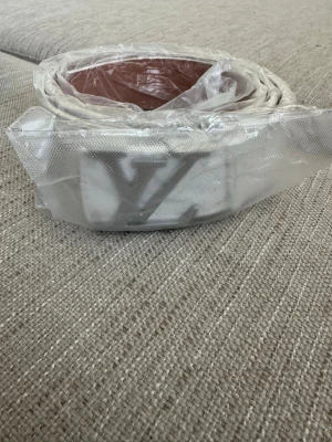 Vitt bälte med metallspänne - Säljer ett vitt bälte med ett stort metallspänne i silverfärg. Bältet är slätt och har en klassisk design, perfekt för att lyfta vilken outfit som helst. Kommer i plastförpackning.