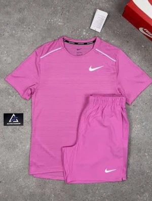 Rosa träningsset från Nike - Säljer ett rosa träningsset från Nike med t-shirt och shorts. T-shirten har rund hals, diskreta ränder och vita detaljer vid axlarna samt Nike-logga på bröstet. Shortsen har resår i midjan och vit Nike-logga på benet. Perfekt för gym eller löpning.