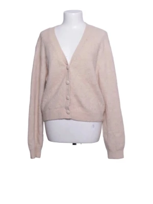 Ljusbeige fluffig kofta med knappar - Mysig beige kofta med v-ringning och stora matchande knappar framtill. Koftan är gjord i ett mjukt material som ger en avslappnad och trendig look. Från & other stories i storlek s-m
