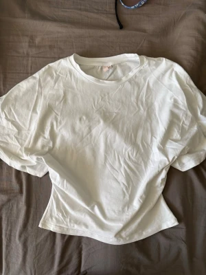 Vit basic t-shirt från Nelly - En enkel och stilren vit t-shirt från Nelly i mjuk bomull. T-shirten har rund halsringning och korta ärmar, perfekt till alla dina outfits. Passformen är normal och tyget känns lätt och bekvämt mot huden.