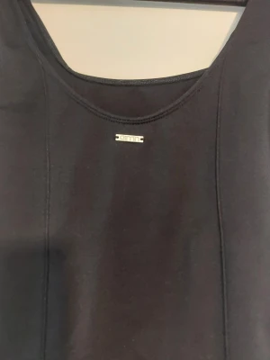 Svarta bodysuit med metallogo - Snygga svarta bodysuit med en liten metallog.. De har en tight passform och är tillverkade i ett stretchigt material som sitter skönt på kroppen. Perfekta för en trendig och bekväm look.