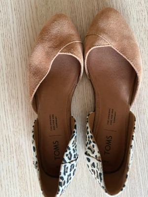 Beige ballerinaskor från TOMS - Jag säljer dessa fina beiga ballerinaskorna från Toms med leopard mönster där bak. De är använda 1 gång så de är i topp skick och passar perfekt till alla outfits! De är i storlek W6💞 Skriv vid minsta funderingar 💕