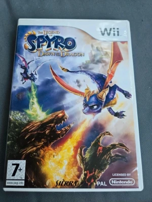 The Legend of Spyro: Dawn of the Dragon Wii - The Legend of Spyro: Dawn of the Dragon till Nintendo Wii. Äventyrsspel där du spelar som drakarna Spyro och Cynder. Omslaget har färgstarka illustrationer med blå, lila och orange toner. Spelet är för 7 år och uppåt och har co-op-läge. PAL-version.
