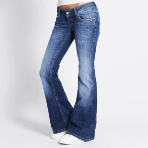 Blå bootcut jeans med låg midja - Snygga blå jeans med bootcut-modell och låg midja. Jeansen har klassisk femficksdesign, lätt slitna detaljer och är tillverkade i mjukt denimtyg. Perfekta för en avslappnad och trendig look. Short length, storlek XS