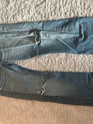 Blå jeans från ZARA - Säljer ett par blå jeans från ZARA med slitna detaljer och stora hål på benen. Jeansen har en lösare passform, som är väldigt trendig just idag! Använd fåtal gånger. Skriv privat om ni har frågor eller vill ha fler bilder etc💕💕