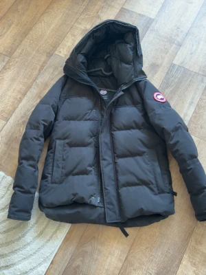 Svart dunjacka från Canada Goose - Säljer min canada goose macmillan använd 2 vintrar enda felet är snöret man hänger jacken med som man ser på bilder men ingen stor grej annars som ny riktigt bra skick, äkta såklart kvitto finns.