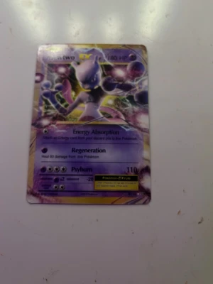 Pokémonkort Mewtwo EX - Säljer ett Pokémonkort med Mewtwo EX-motiv. Kortet har en holografisk yta och visar Mewtwo i en kraftfull pose med lila och gula detaljer. Text och effekter som Energy Absorption, Regeneration och Psyburn finns på kortet. Perfekt för samlare eller Pokémonfans.