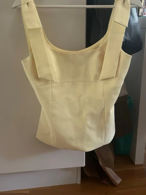 Ljusgul topp - Säljer en ljusgul, figurnära linnetopp! Toppen har en stilren och minimalistisk design som ger en modern look. Perfekt att styla med jeans eller kjol för en trendig outfit.