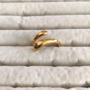 Guldpläterad böjd ring - Snygg och modern ring i guldpläterad med böjd, öppen design. Ringen har en blank yta och en unik form som sticker ut. Perfekt för dig som gillar minimalistiska och trendiga smycken.