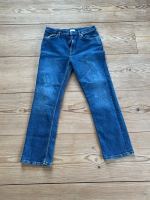 Blå raka jeans från GANT - Säljer ett par klassiska blå jeans från GANT med rak passform och fem fickor. Jeansen har snygga slitningar och kontrastsömmar som ger en tidlös look. Perfekta till vardags och passar till det mesta i garderoben.