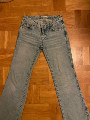 Ljusblå bootcut jeans med fickor - Säljer ett par ljusblå bootcut jeans med klassisk femficksdesign och extra ficklock bak. Jeansen har låg midja med lätt utsvängning. Tillverkade i denim med snygg tvätt och detaljerade sömmar. Perfekta för en avslappnad och trendig look.