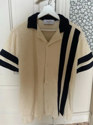  Skjorta från Les Deux - Beige skjorta från Les Deux. Skjortan har svart krage, knappar framtill och är gjord i mjuk frotté. Stl S men passar ännu bättre M. Endast testad. 