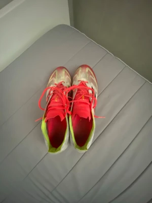  Adidas F50 Elite AG - Säljer ett par snygga Adidas fotbollsskor i vitt med svarta ränder och rosa detaljer. Skorna har snörning, neonfärgade insidor och är tillverkade i syntetmaterial för bra grepp och känsla på planen. Perfekta för dig som vill sticka ut på matchen!