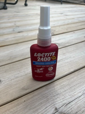 Loctite 2400 gänglåsning 50 ml - Loctite 2400 gänglåsning i röd plastflaska med vitt munstycke. Flaskan innehåller 50 ml och används för att säkra och täta gängade förband. Märkt med Henkel och har tydliga instruktioner på etiketten.