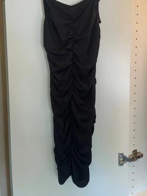 Svart långklänning från SHEIN Teen - Snygg svart långklänning från SHEIN Teen med rynkade detaljer längs hela framsidan. Klänningen har smala axelband och en figurnära passform som ger en trendig look.