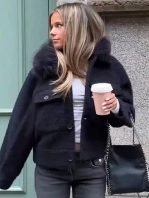 Svart teddyjacka med huva - Mysig mörkbrun teddyjacka med fluffig huva och två stora bröstfickor. Jackan har knäppning framtill och är tillverkad i ett mjukt, lurvigt material som håller dig varm. Perfekt för kalla dagar och ger en trendig look.