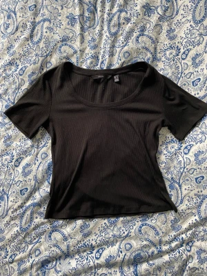 Svart ribbad topp - En svart ribbad topp från Vero Moda med rund halsringning och korta ärmar. Perfekt för alla tillfällen 💕