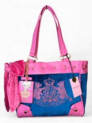 Juicy Couture blå och rosa handväska daydreamer  - Juicy Couture handväska i blått och rosa sammet med rosa detaljer och emblem framtill. Väskan har två axelband, en stor rosa rosett på sidan och guldfärgade metalldetaljer. Perfekt för dig som vill sticka ut med en färgglad och trendig accessoar.