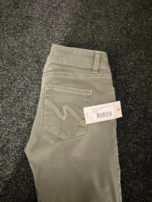 Gröna lågmidjade bootcut jeans - Säljer ett par Nelly jeans då de ej var rätt storlek för mig. Helt oanvända och prislappen är kvar! 🥰