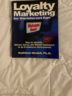 Loyalty Marketing for the Internet Age - Boken 'Loyalty Marketing for the Internet Age' av Kathleen Sindell, Ph.D., handlar om hur man identifierar, attraherar, servar och behåller kunder i en e-handelsmiljö. Omslaget är blått med vit och gul text samt en datorgrafik. Perfekt för dig som vill lära dig mer om kundlojalitet online.
