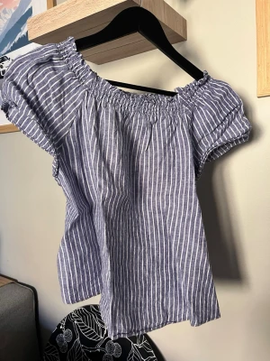 Randig offshoulder blus i bomull - Säljer en blåvit randig offshoulder blus med korta ärmar. Luftig och skön för varma dagar. Passar dig som gillar en avslappnad och trendig stil.