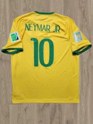 Nike Brazil 2014 World Cup tröja - Brasilien VM 2014 fotbollströja från Nike med Neymar Jr och nummer 10 på ryggen. Tröjan har gröna detaljer vid krage och ärmslut, officiella VM-märken och FIFA  på ärmarna. 