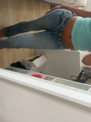 Ljusblå low waist jeans bootcut - Säljer ett par ljusblå jeans med låg midja och bootcut-modell. Jeansen har klassisk femficksdesign och är gjorda i denim med lätt tvättad look. Perfekta för en avslappnad och trendig stil.
