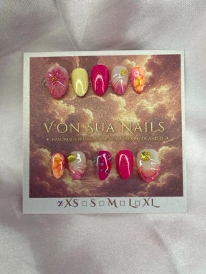 Marea (XS);ExtraShortAlmond  - Handgjorda press-on nails i rosa, korall och mjuka nude-toner med havsinspirerade detaljer. Setet kombinerar handmålade blommor, fiskmotiv, skimrande färger och guldfärgade snäckdetaljer. Varje nagel är handgjord för ett färgstarkt och unikt uttryck.  Form: Extra Short Almond Storlek: XS 10 naglar ingår