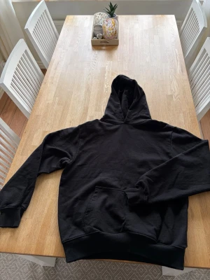 Svart hoodie från Zara - En klassisk svart hoodie med huva och stor magficka framtill. Hoodien har ribbade muddar vid ärmslut och nederkant. Hoodien har en boxig modell. Modellen på andra bilden är 183cm.