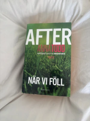 After: När vi föll av Anna Todd - En ungdomsroman från Anna Todd, del i den populära After-serien. Omslaget är grönt med vit och rosa text och motiv av gräs. Boken är utgiven av Norstedts och handlar om kärlek, drama och relationer.