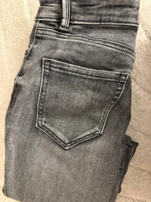 Grå bootcut jeans med fickor - Snygga grå jeans med bootcut-modell och klassiska fem fickor. Jeansen har en tvättad look och raka ben som går ut lite nedtill. Perfekta för dig som gillar en avslappnad men trendig stil.