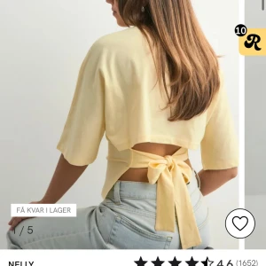 Gul topp med knyt från Nelly - Säljer en ljusgul omlottopp från Nelly med korta ärmar och snygg öppen rygg. Toppen har ett brett band som knyts i ryggen för en trendig look. Perfekt till jeans eller kjol för en fräsch stil. 