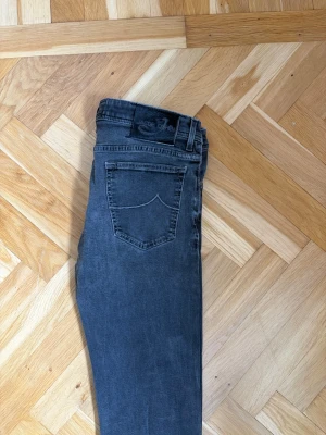 Grå jeans från Jacob Cohen - Snygga grå jeans från Jacob Cohen med raka ben och klassisk femficksmodell. Jeansen har knäppning med knappar framtill och diskret logga på bakfickan. Tillverkade i mjukt denimtyg som ger en skön passform och stilren look.