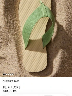 Beige flip-flops med gröna band - Snygga flip-flops med beige sula och breda, ljusgröna textilband. Sulan har en lätt struktur för extra komfort och grepp. Perfekta för sommardagar på stranden eller i stan. Enkel och stilren design som passar till det mesta. Helt nya! Ej använda.