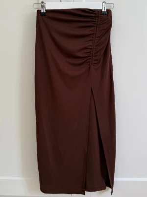 Brun långkjol med slits och rynk - Snygg brun långkjol, rynkade detaljer framtill och en stilren slits på ena sidan. Kjolen har en rak passform och är tillverkad i ett mjukt, följsamt material som ger en elegant look💗