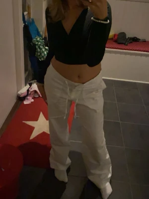 Vita linnebyxor med dragsko - Säljer ett par vita linnebyxor med avslappnad passform och dragsko i midjan. Byxorna har raka ben och är perfekta för en chill och stilren look. Materialet är lätt och luftigt, vilket gör dem sköna att bära under varmare dagar.