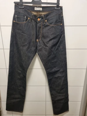 Mörkblå Acne Jeans raka - Säljer ett par mörkblå raka jeans från Acne Jeans. Klassisk femficksmodell med kontrastsömmar och knappgylf. Jeansen är i kraftig denim och har en tidlös look som passar till det mesta. Perfekta för dig som gillar stilrena och snygga jeans.